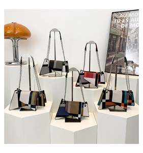 Detail display of geometric patchwork shoulder bags in various colors with metal chains