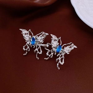 Détail de broches papillon argentées avec pierres bleues sur fond de tissu foncé
