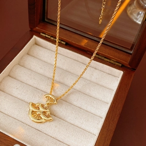 Détail du collier à pendentif éventail doré sur velours beige dans un coffret en bois rétro
