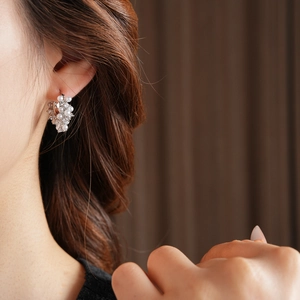 Elegant U-shaped silver earring with pearl and zircon inlay worn on a female ear