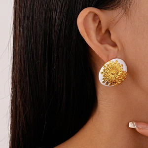 Close-up of a model wearing vintage round gold daisy earrings with white enamel finish