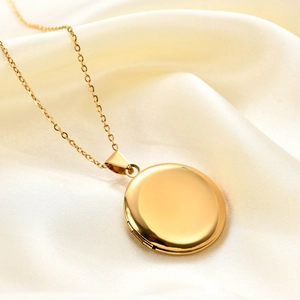 Detailed view of an oval gold locket necklace with a polished finish on white silk