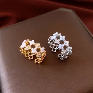 Bagues ajourées dorées et argentées avec perles et zircons sur un fond de soie riche