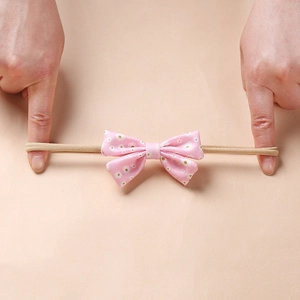 Detail showing the high elasticity of the pink floral baby bow headband being stretched