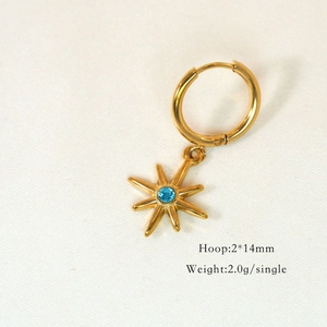 Detailed view of golden hoop earring with octagonal star charm and blue gemstone inlay