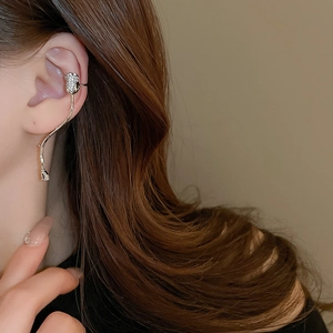 Close-up of a silver tassel ear cuff with sparkling zircons worn by a female model