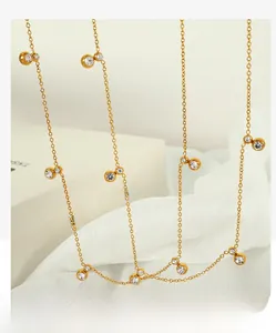Detailed close-up of gold necklace with round zircon accents on white fabric