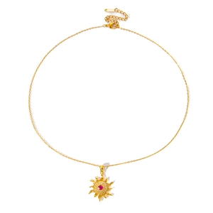Detailed close-up of a golden sun pendant with a red stone and crystal halo inlay
