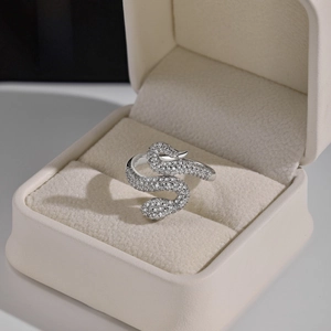 Macro shot of silver snake-shaped ring with pavé-set zircons in a beige jewelry gift box