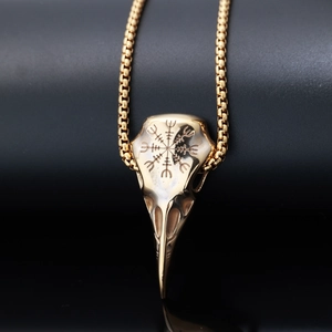 Macro shot of golden crow skull pendant with Nordic Vegvisir compass engraving