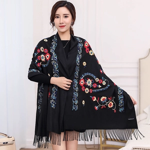 Close-up of floral embroidery and fringe detail on a black cashmere-style shawl