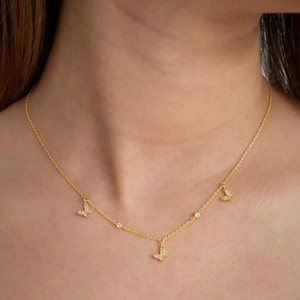 Close-up of gold butterfly necklace with zircon accents on a model neck