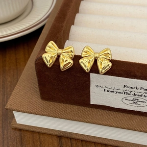 Detailed macro view of gold bow knot earrings with polished texture on velvet