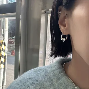Close-up of minimalist 925 sterling silver earrings and CK logo ear cuff on model