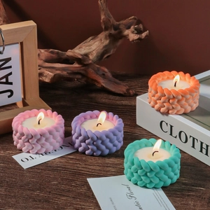Close-up of lit cylindrical knit texture scented candles in multiple warm colors