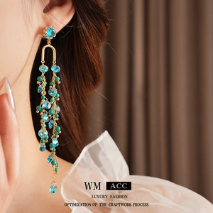 Exquisite gold long tassel earrings with blue crystals and beads worn by a model
