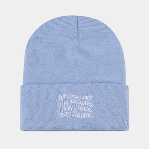 Detail of light blue ribbed knit beanie with white embroidered inspirational quote