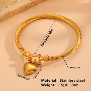 Luxurious gold stainless steel twisted cable bangle with heart pendant on stone surface