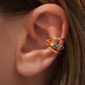 Detail of double-layer gold ear cuff with colorful zircon stones worn on the ear