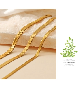 Detailed close-up of three widths of golden snake chain bracelets on white stone