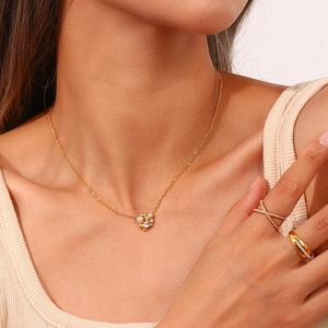 Detail of 18K gold-plated floral pearl pendant necklace and sparkling CZ rings on a model
