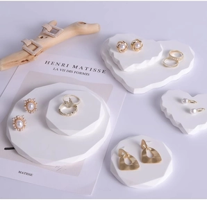 Detail of gold earrings and pearl studs on geometric plaster display stands