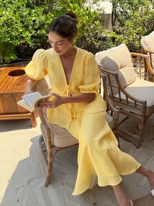 Close-up of a yellow linen V-neck set with puff sleeves in a sunny garden setting