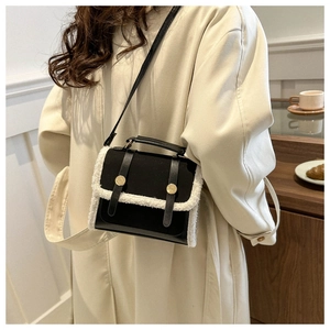 Detail of vintage black crossbody bag with white plush trim and golden metal buckles