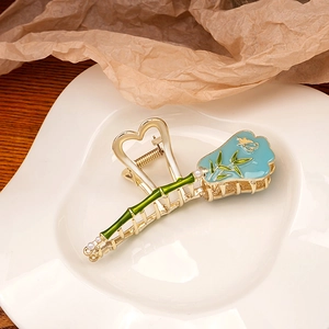Detail of vintage gold metal hair claw with green bamboo and blue enamel flowers