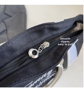 Detail of the top silver circular metal zipper and white embroidery on a black bowling bag