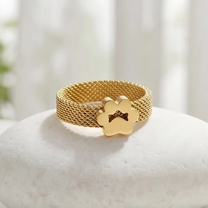 Detailed view of golden mesh stainless steel ring with flower charm on white stone