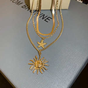 Detailed close-up of layered gold necklaces with sun relief and starfish pendants