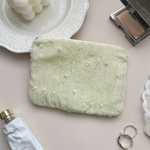 Flat lay of green chiffon flower cosmetic pouch with embroidery and gold zipper detail