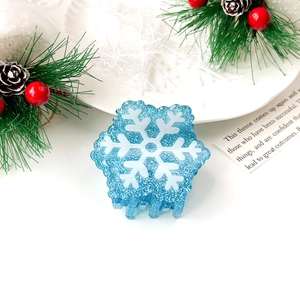 Detail view of light blue glitter hair claw clip with large white snowflake pattern