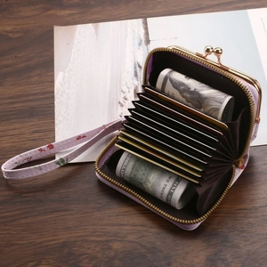 Purple floral coin purse with kiss-lock, wrist strap, and multiple card slots on wood