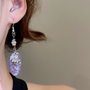 Detail of purple marble resin earrings with silver floral accents and pearls
