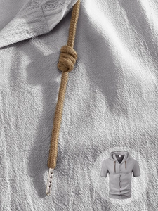 Dettaglio del tessuto in lino grigio della camicia con cappuccio e lacci intrecciati marroni