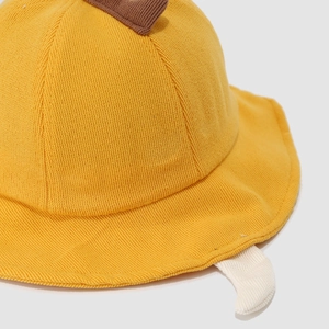 Detail of yellow knit toddler bucket hat with cute dinosaur 3D horns and soft texture