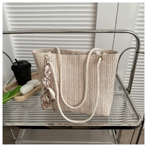 Détail du sac cabas en paille tressée avec foulard en soie sur un chariot argenté