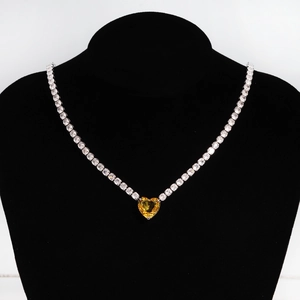 Detail of silver necklace with yellow heart zircon pendant on black mannequin