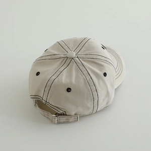 Detail view of washed denim baseball cap with contrast black stitching and metal buckle