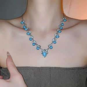 Detailed shot of ethnic necklace featuring teardrop turquoise pendant on a silver chain
