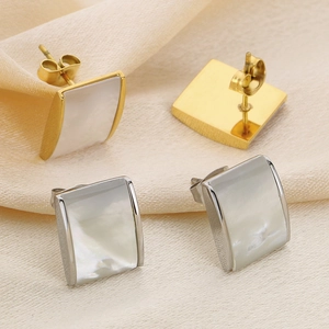 Macro detail of square shell stud earrings in gold and silver with satin background