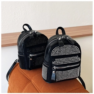 Detalle de mochila negra con pedrería decorada con tachuelas plateadas y cremalleras