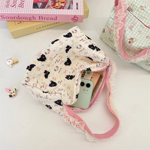 Detail view of lace canvas tote bag with black cat and puppy cartoon illustrations