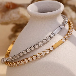 Close-up of gold and silver zircon bracelets wrapped around white ceramic decor