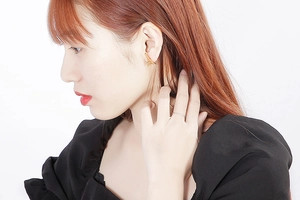 Gros plan de boucles d'oreilles pyramide Tour Eiffel dorées et bague argentée minimaliste