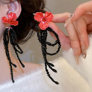 Gros plan de boucles d'oreilles fleurs rouges avec pompons en cristal noir sur modèle