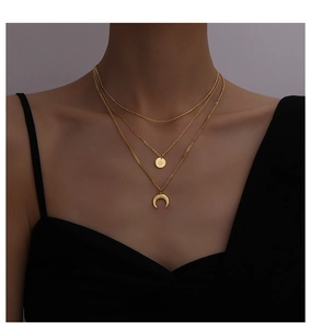 Detail of layered gold necklace with moon and round pendants on model neck