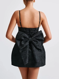 Rear view of black mini dress featuring a large bow detail and subtle floral jacquard fabric